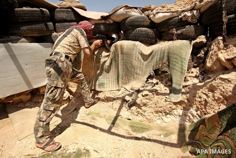 A fighter from the Free Syrian Army takes position following clashes with the pro-regime forces, in Aziza village in the northern Syrian city of Aleppo, on July 28, 2015. Photo by Ameer al-Halbi