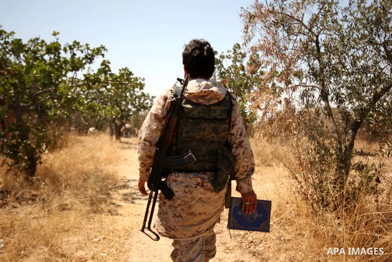 A Fighter from the Free Syrian Army holds a copy of Quran as he patrols the area following clashes with the pro-regime forces, in Aziza village in the northern Syrian city of Aleppo, on July 28, 2015. Photo by Ameer al-H...