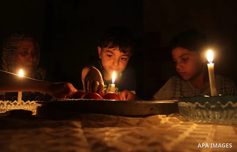 Palestinian family use a candle light as they eat dinner during a power cut in Rafah in the southern Gaza Strip, on July 28, 2015. Independent Commission for Human Rights warned Saturday of the aggravated humanitarian si...