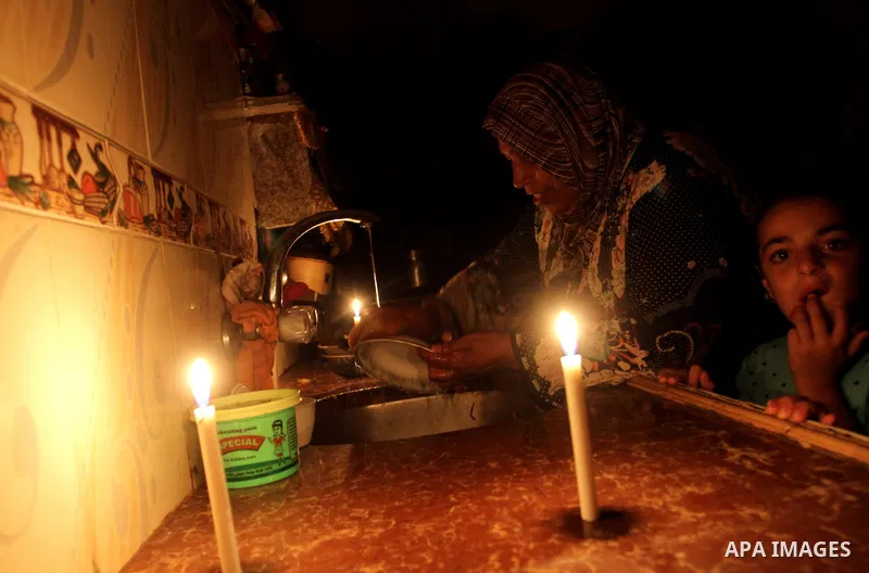 Palestinian family use a candle light during a power cut in Rafah in the southern Gaza Strip, on July 28, 2015. Independent Commission for Human Rights warned Saturday of the aggravated humanitarian situation in Gaza due...