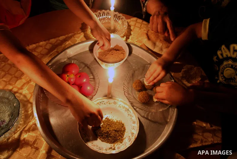 Palestinian family use a candle light as they eat dinner during a power cut in Rafah in the southern Gaza Strip, on July 28, 2015. Independent Commission for Human Rights warned Saturday of the aggravated humanitarian si...