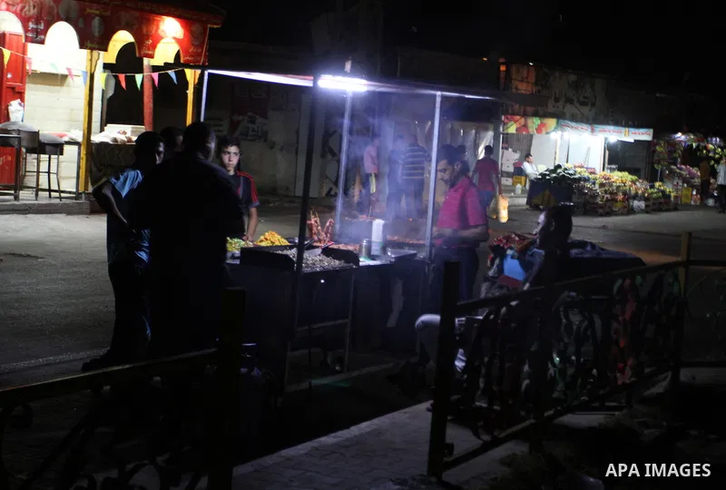 A Palestinian man prepares a falafel as he uses a candle light during a power cut in Rafah in the southern Gaza Strip, on July 28, 2015. Independent Commission for Human Rights warned Saturday of the aggravated humanitar...