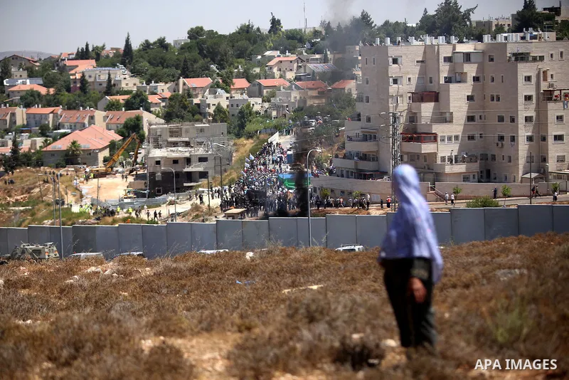 A Palestinian woman, watches Israeli heavy machinery as they demolish vacant apartment blocs by order of Israel's high court, in the West Bank Jewish settlement of Beit El near Ramallah July 29, 2015. Israel gave final a...