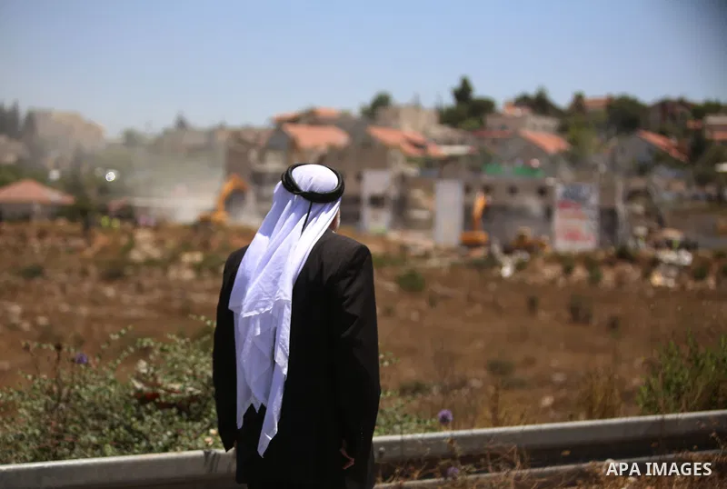 Palestinian Abdul Rahman Qasim, watches Israeli heavy machinery as they demolish vacant apartment blocs by order of Israel's high court, in the West Bank Jewish settlement of Beit El near Ramallah July 29, 2015. Israel g...