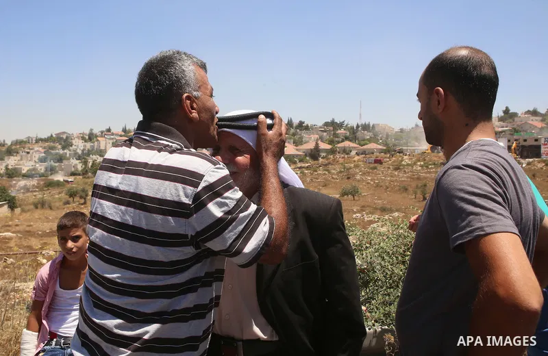 Palestinian man kisses the head of Abdul Rahman Qasim, as Israeli machinery demolish his vacant apartment blocs by order of Israel's high court, in the West Bank Jewish settlement of Beit El near Ramallah July 29, 2015....