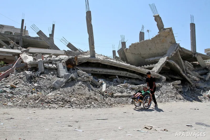 A Palestinian boy pushes the wheelchair of his brother, Ayman Mahmoum, who was injured during the 50-day war between Israel and Hamas militants in the summer of 2014, in Rafah in the southern Gaza Strip on July 29, 2015....