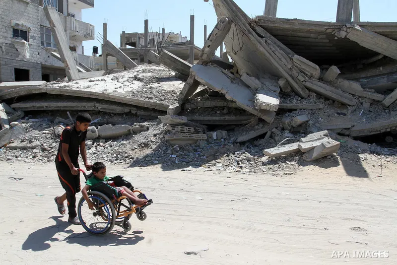 A Palestinian boy pushes the wheelchair of his brother, Ayman Mahmoum, who was injured during the 50-day war between Israel and Hamas militants in the summer of 2014, in Rafah in the southern Gaza Strip on July 29, 2015....