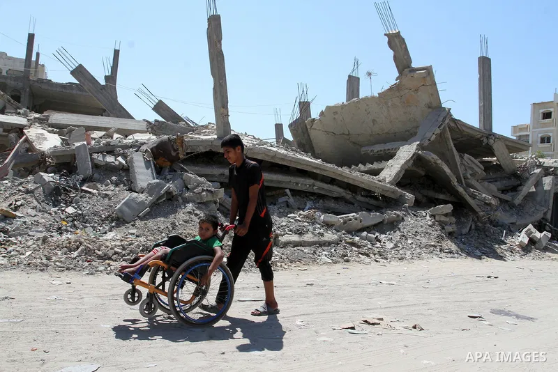 A Palestinian boy pushes the wheelchair of his brother, Ayman Mahmoum, who was injured during the 50-day war between Israel and Hamas militants in the summer of 2014, in Rafah in the southern Gaza Strip on July 29, 2015....