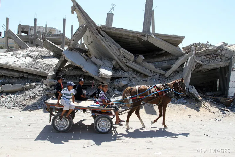 Palestinian children ride a horse cart past the rubble of a house, which was destroyed during the 50-day war between Israel and Hamas militants in the summer of 2014, in Rafah in the southern Gaza Strip on July 29, 2015....