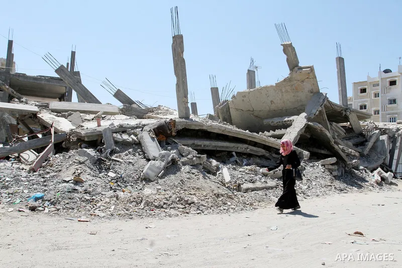 A Palestinian woman walks past the rubble of a house, which was destroyed during the 50-day war between Israel and Hamas militants in the summer of 2014, in Rafah in the southern Gaza Strip on July 29, 2015. An analysis...