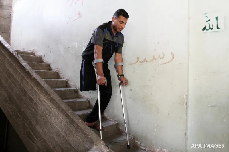 Palestinian Wael al-Namla, who was injured during the 50-day war between Israel and Hamas militants in the summer of 2014, steps down the stairs with crutches at his house on July 30, 2015 in Rafah in the southern Gaza S...