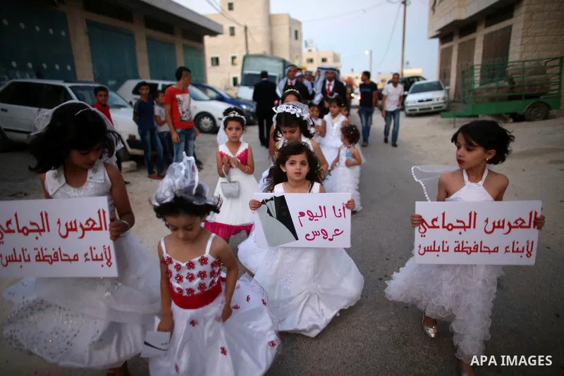 Palestinian girls attend a mass wedding ceremony in the West Bank city of Nablus, on July 30, 2015. Nearly 120 Palestinian couples were married in a ceremony supported by Palestinian President Mahmoud Abbas. Photo by Ahm...