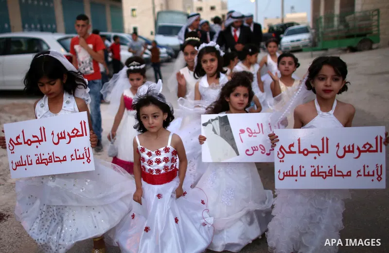 Palestinian girls attend a mass wedding ceremony in the West Bank city of Nablus, on July 30, 2015. Nearly 120 Palestinian couples were married in a ceremony supported by Palestinian President Mahmoud Abbas. Photo by Ahm...