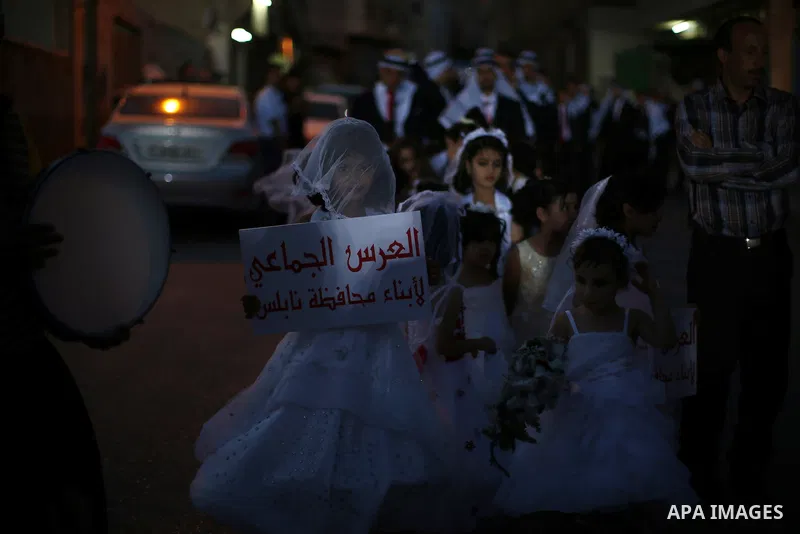 Palestinian girls attend a mass wedding ceremony in the West Bank city of Nablus, on July 30, 2015. Nearly 120 Palestinian couples were married in a ceremony supported by Palestinian President Mahmoud Abbas. Photo by Ahm...