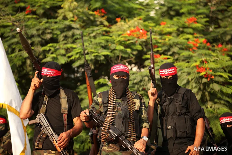 Masked Palestinian militants of the National Resistance Brigades, a group linked to the Democratic Front for the Liberation of Palestine hold their weapons during a military parade against the killing of a 18-month-old P...