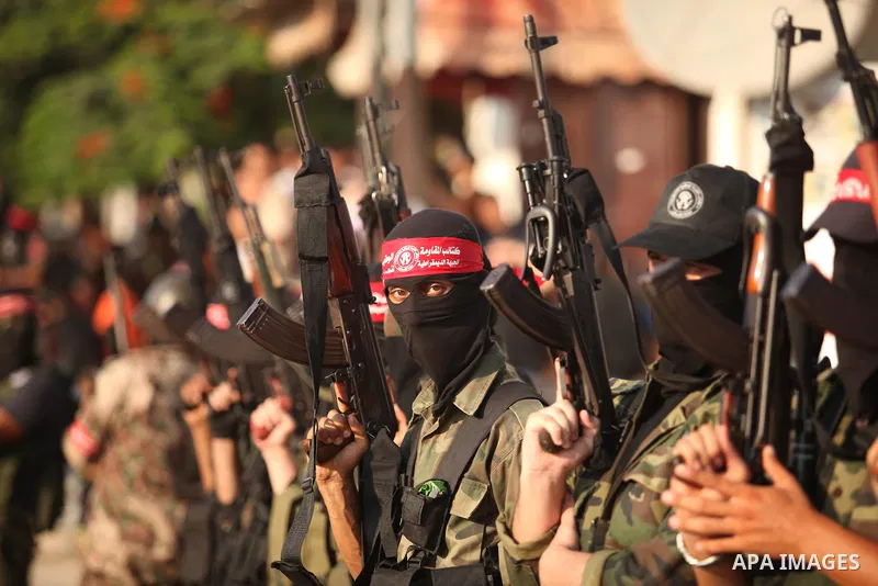 Masked Palestinian militants of the National Resistance Brigades, a group linked to the Democratic Front for the Liberation of Palestine hold their weapons during a military parade against the killing of a 18-month-old P...