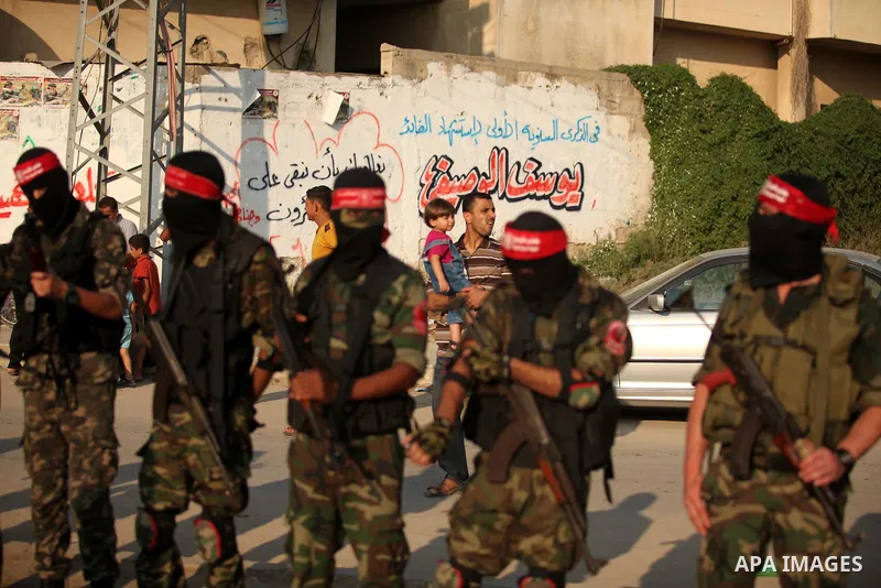 Masked Palestinian militants of the National Resistance Brigades, a group linked to the Democratic Front for the Liberation of Palestine hold their weapons during a military parade against the killing of a 18-month-old P...