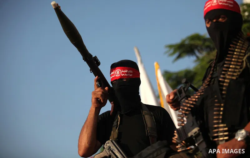 Masked Palestinian militants of the National Resistance Brigades, a group linked to the Democratic Front for the Liberation of Palestine hold their weapons during a military parade against the killing of a 18-month-old P...