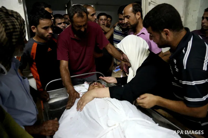 The mother of Mohammed al-Masri, 17, mourns over his body at a hospital morgue, in Beit Lahia in the northern Gaza Strip on July 31, 2015. Al-Masri killed and another wounded after being shot by Israeli gunfire in the no...
