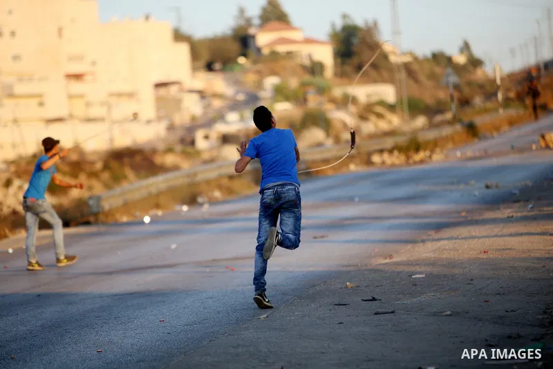 Palestinian protesters use slingshots during clashes with Israeli security forces earby the Jalazoun refugee camp and the Jewish settlement of Beit El, north of Ramallah, after a demonstration in reaction to the death of...