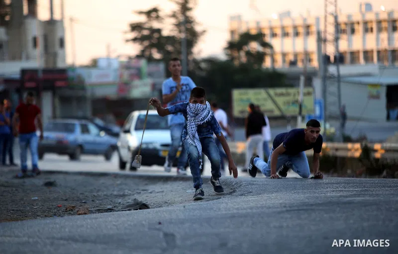 A Palestinian protester uses a slingshot during clashes with Israeli security forces earby the Jalazoun refugee camp and the Jewish settlement of Beit El, north of Ramallah, after a demonstration in reaction to the death...