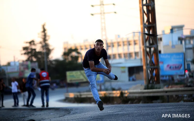 A Palestinian protester uses a slingshot during clashes with Israeli security forces earby the Jalazoun refugee camp and the Jewish settlement of Beit El, north of Ramallah, after a demonstration in reaction to the death...