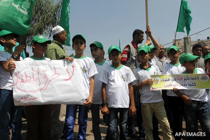 Palestinian children hold banners during the announcement of the start of summer camps organized by the Hamas movement in Gaza city on August 1, 2015. Photo by Mohammed Asad