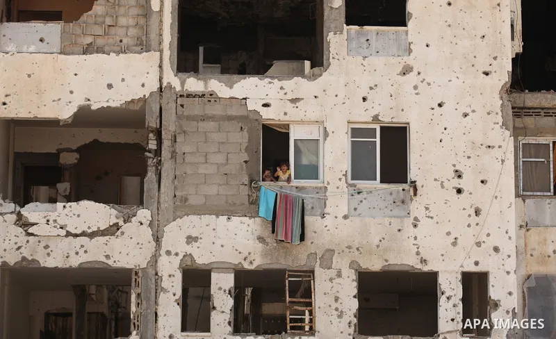 Palestinian children look through a window from their house, which was destroyed during the 50-day Israeli war in the summer of 2014, in Beit Lahia in the northern Gaza Strip on August 1, 2015. Photo by Ashraf Amra