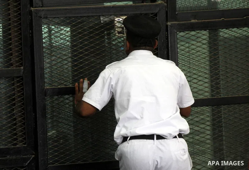 An Egyptian policeman speaks to defendants during the trial of Egyptian radical Islamist Mohammed al-Zawahiri, the brother of Al-Qaeda chief Ayman al-Zawahiri with 68 other defendants, at a court in Cairo on August 01, 2...