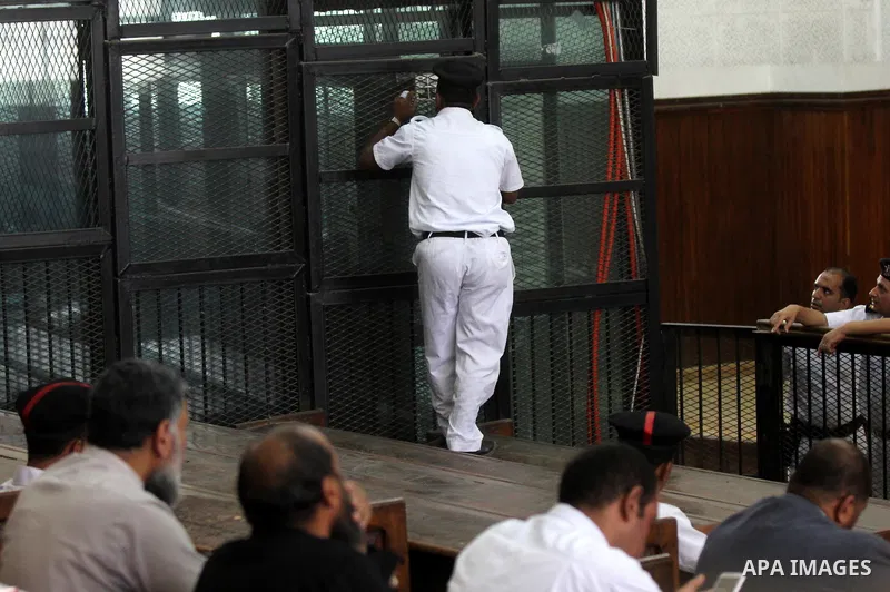 An Egyptian policeman speaks to defendants during the trial of Egyptian radical Islamist Mohammed al-Zawahiri, the brother of Al-Qaeda chief Ayman al-Zawahiri with 68 other defendants, at a court in Cairo on August 01, 2...