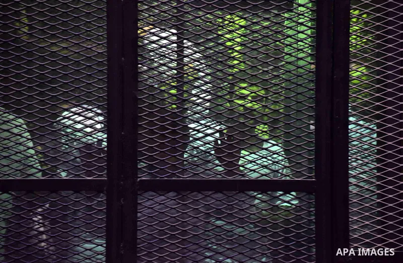 Egyptians defendants in Boulaq riots case, stand behind bars during their trial at a court in Cairo on August 01, 2015. Cairo Criminal Court delayed the trial of 379 Muslim Brotherhood (MB) members over charges of illega...