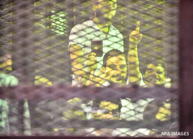 Egyptians defendants in Boulaq riots case, stand behind bars during their trial at a court in Cairo on August 01, 2015. Cairo Criminal Court delayed the trial of 379 Muslim Brotherhood (MB) members over charges of illega...