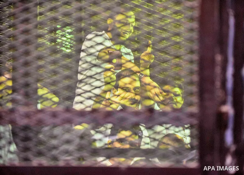 Egyptians defendants in Boulaq riots case, stand behind bars during their trial at a court in Cairo on August 01, 2015. Cairo Criminal Court delayed the trial of 379 Muslim Brotherhood (MB) members over charges of illega...