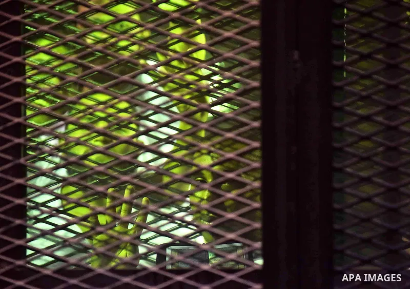Egyptians defendants in Boulaq riots case, stand behind bars during their trial at a court in Cairo on August 01, 2015. Cairo Criminal Court delayed the trial of 379 Muslim Brotherhood (MB) members over charges of illega...