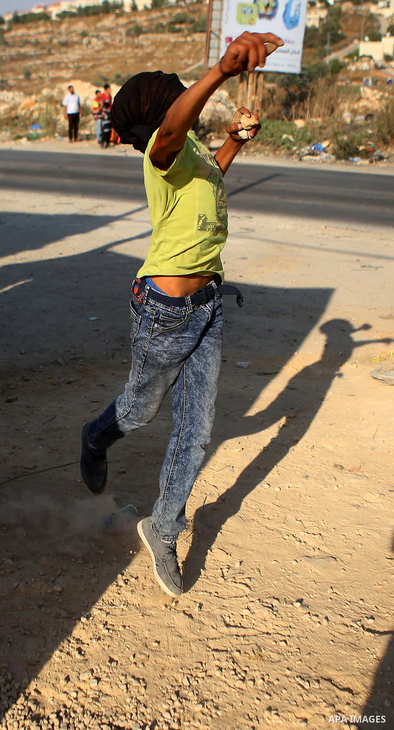 A Palestinian protester throws stones during clashes with Israeli security forces earby the Jalazoun refugee camp and the Jewish settlement of Beit El, north of Ramallah in reaction to the death of Palestinian youth Lait...