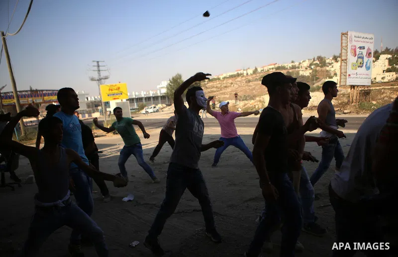 Palestinian protesters throw stones during clashes with Israeli security forces earby the Jalazoun refugee camp and the Jewish settlement of Beit El, north of Ramallah in reaction to the death of Palestinian youth Laith...