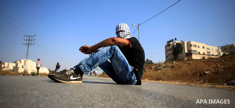 A masked Palestinian demonstrator rests on the asphalt during clashes with Israeli security forces earby the Jalazoun refugee camp and the Jewish settlement of Beit El, north of Ramallah in reaction to the death of Pales...