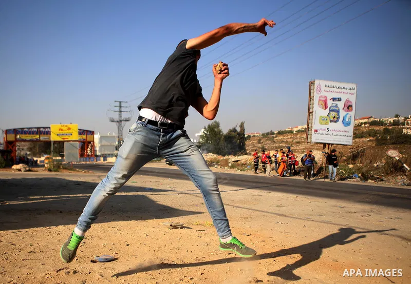A Palestinian protester throws stones during clashes with Israeli security forces earby the Jalazoun refugee camp and the Jewish settlement of Beit El, north of Ramallah in reaction to the death of Palestinian youth Lait...