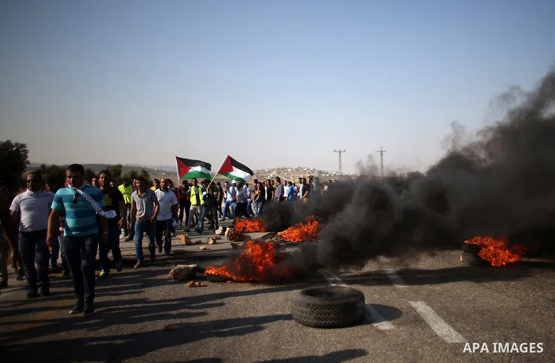 Palestinian protesters hold national flages during clashes at the entrance to Duma village near the West Bank city of Nablus, Saturday, Aug. 1, 2015. Tensions remain high after suspected Jewish assailants set fire to a W...