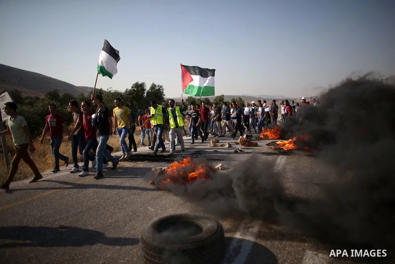 Palestinian protesters hold national flages during clashes at the entrance to Duma village near the West Bank city of Nablus, Saturday, Aug. 1, 2015. Tensions remain high after suspected Jewish assailants set fire to a W...
