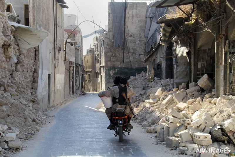 Fighters from the Free Syrian Army ride motorcycle past the rubble of buildings which destroyed by Syrian government forces in the old quarter of the northern Syrian city of Aleppo on August 01, 2015. Photo by Ameer al-H...