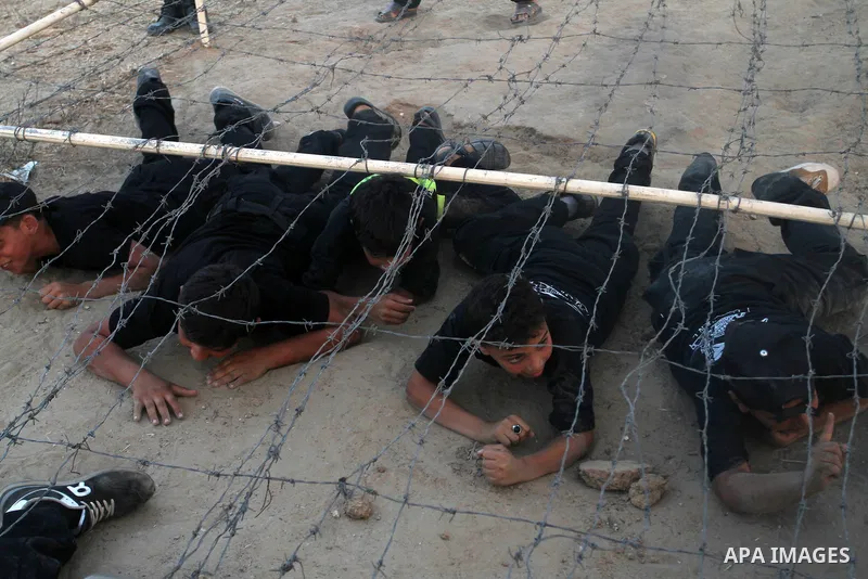 Young Palestinians crawl under an obstacle during a military-style exercise at Liberation Youths summer camp, organised by the Hamas movement, in Rafah in the southern Gaza Strip, August 1, 2015. Hamas stages dozens of m...