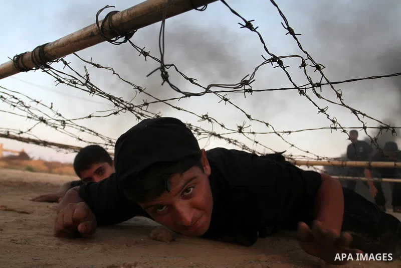 Young Palestinians crawl under an obstacle during a military-style exercise at Liberation Youths summer camp, organised by the Hamas movement, in Rafah in the southern Gaza Strip, August 1, 2015. Hamas stages dozens of m...