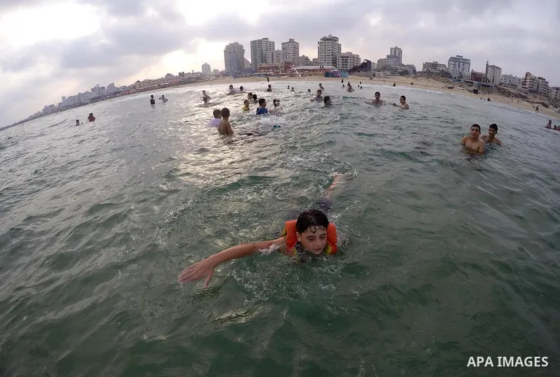 Palestinians enjoy the warm weather on a beach along the Mediterranean Sea in Gaza city, on August 2, 2015. Photo by Mohammed Asad