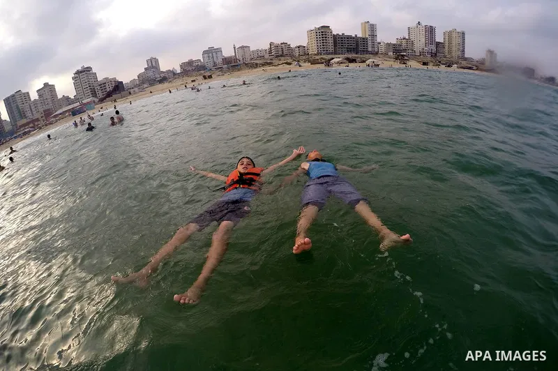 Palestinians enjoy the warm weather on a beach along the Mediterranean Sea in Gaza city, on August 2, 2015. Photo by Mohammed Asad