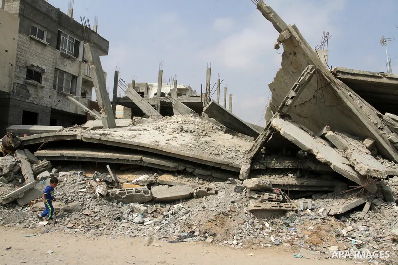 A Palestinian boy walks past the rubble of houses, which were destroyed during the 50-day Israeli war in the summer of 2014, in Rafah in the southern Gaza strip, on August 2, 2015. Photo by Abed Rahim Khatib