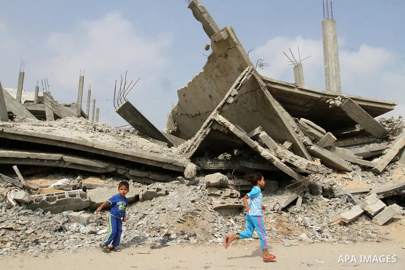 Palestinian boys walk past the rubble of houses, which were destroyed during the 50-day Israeli war in the summer of 2014, in Rafah in the southern Gaza strip, on August 2, 2015. Photo by Abed Rahim Khatib