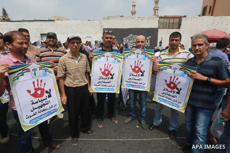 Palestinians hold banners during a protest against the UNRWA decision to reduce of the aid in front of the headquarters United Nations Relief and Works Agency (UNRWA), in Gaza city on August 2, 2015. Photo by Mohammed As...