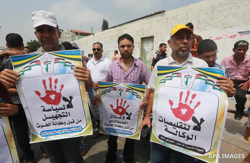 Palestinians hold banners during a protest against the UNRWA decision to reduce of the aid in front of the headquarters United Nations Relief and Works Agency (UNRWA), in Gaza city on August 2, 2015. Photo by Mohammed As...