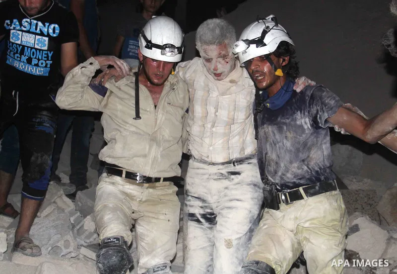 Syrian civil defence members help an injured man following a reported bomb barrel attack by forces of Syria's President Bashar al-Assad at the old city of Aleppo, on August 2, 2015. At least 1 civilian killed 8 others we...